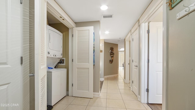 laundry area with laundry area, light tile patterned floors, baseboards, visible vents, and stacked washer / drying machine