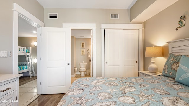 bedroom featuring connected bathroom, visible vents, a closet, and wood finished floors