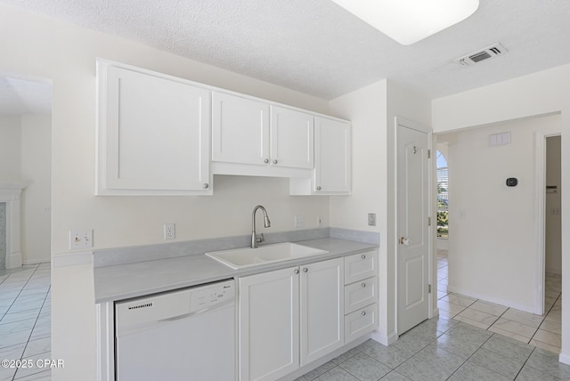 kitchen featuring visible vents, white cabinets, white dishwasher, light countertops, and a sink