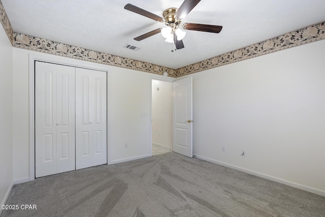 unfurnished bedroom featuring carpet, a closet, visible vents, a textured ceiling, and baseboards