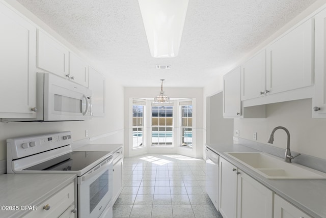 kitchen featuring light tile patterned floors, white appliances, a sink, white cabinetry, and light countertops