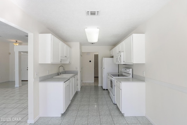 kitchen with light countertops, white appliances, visible vents, and a sink