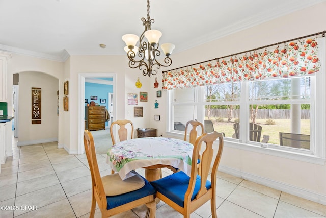 dining area with light tile patterned floors, arched walkways, and ornamental molding