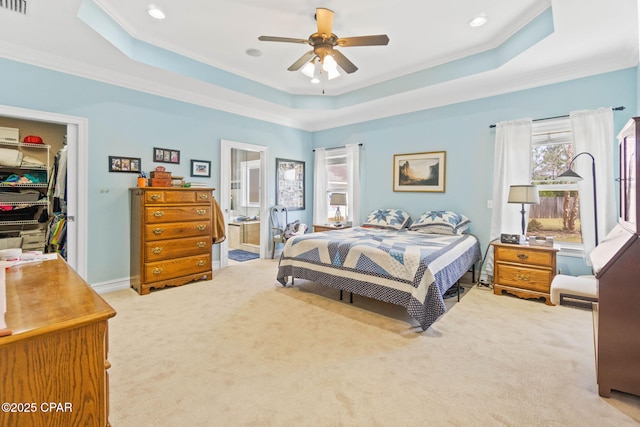 bedroom featuring a walk in closet, crown molding, light colored carpet, and a raised ceiling