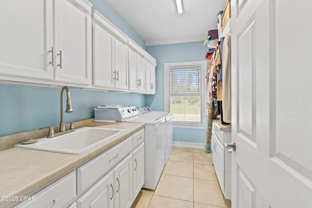 washroom featuring ornamental molding, a sink, cabinet space, separate washer and dryer, and light tile patterned flooring