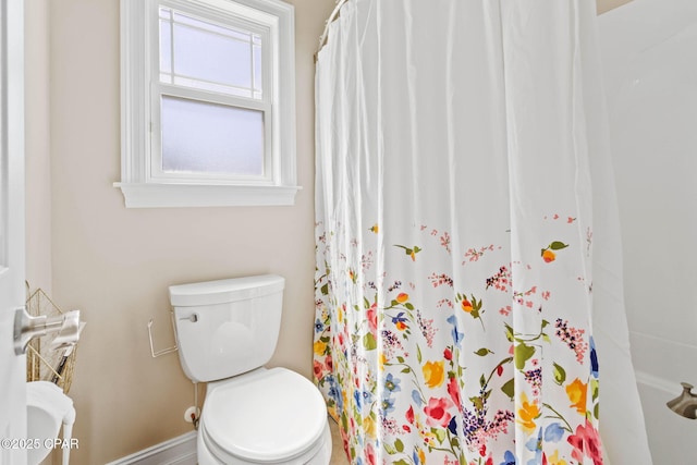 bathroom with curtained shower, baseboards, and toilet