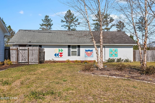 view of front of home featuring a front yard, fence, and a shingled roof