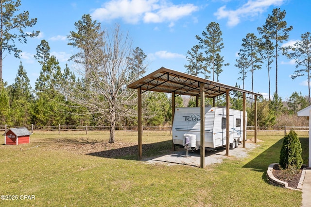 view of yard with a detached carport, an outbuilding, driveway, and a fenced backyard