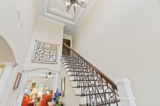 stairs featuring ornamental molding, ornate columns, a towering ceiling, arched walkways, and a ceiling fan