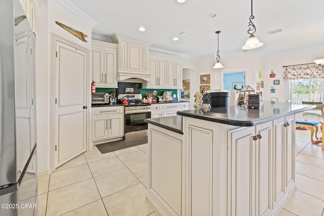 kitchen with dark countertops, visible vents, a kitchen island, light tile patterned floors, and electric range