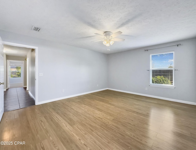 spare room with ceiling fan, a textured ceiling, a healthy amount of sunlight, and wood finished floors