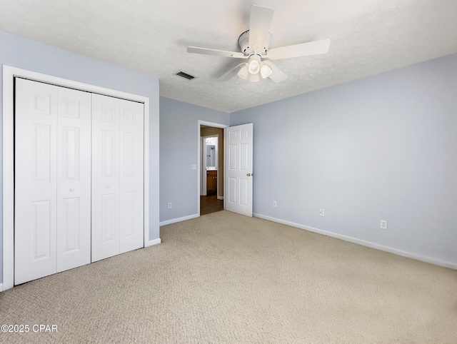 unfurnished bedroom with baseboards, visible vents, carpet floors, a closet, and a textured ceiling