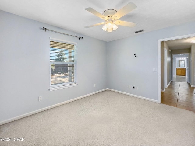 unfurnished room with visible vents, baseboards, carpet, and a ceiling fan