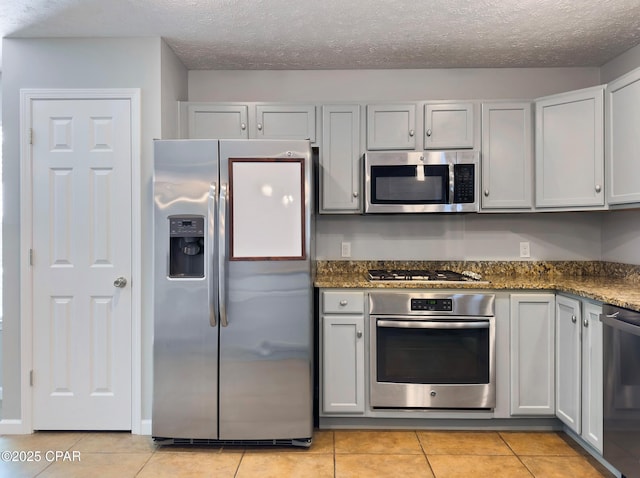 kitchen featuring stainless steel appliances, a textured ceiling, and light tile patterned flooring