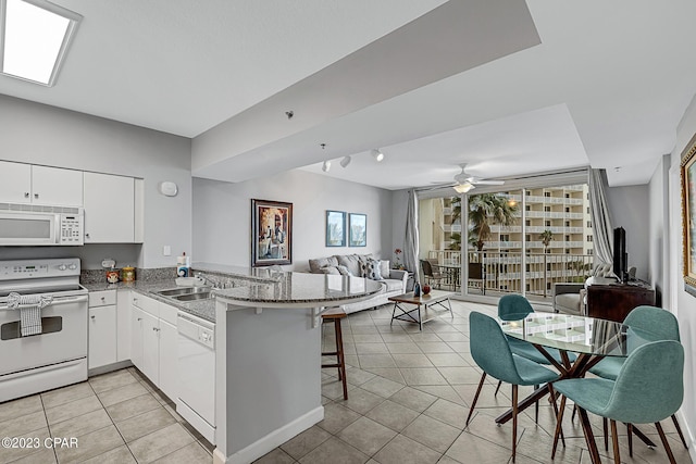 kitchen with white appliances, light tile patterned floors, open floor plan, a peninsula, and a sink