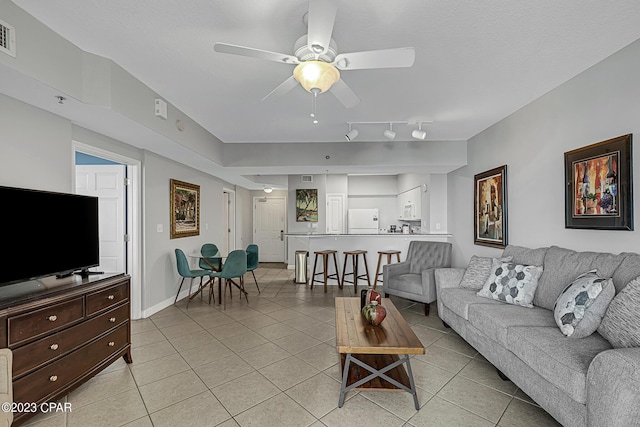 living room with light tile patterned flooring, ceiling fan, visible vents, and baseboards