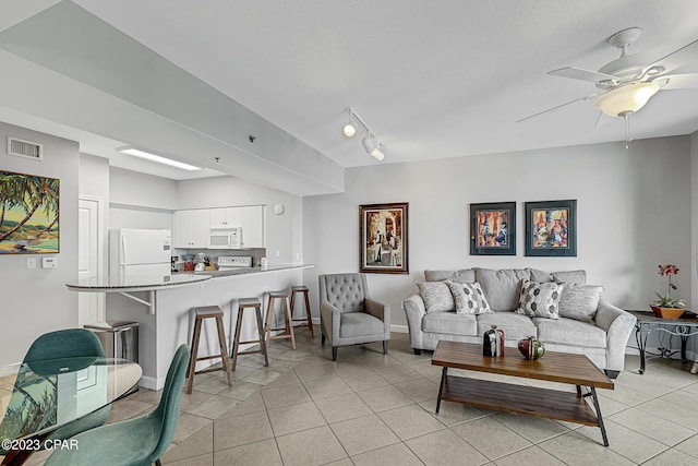 living area featuring light tile patterned floors, ceiling fan, visible vents, baseboards, and rail lighting