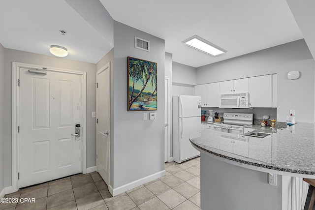 kitchen featuring white appliances, light tile patterned floors, visible vents, a peninsula, and stone counters