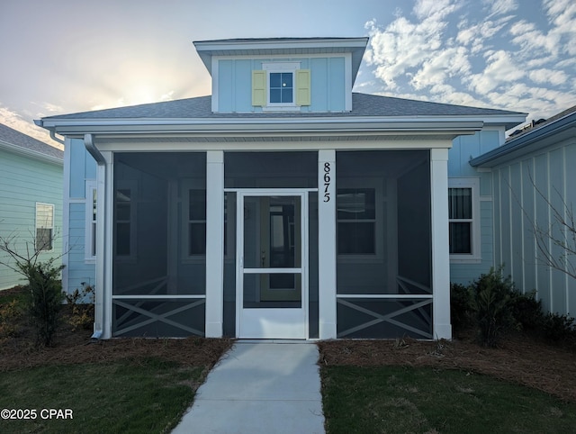 entrance to property with a shingled roof and board and batten siding