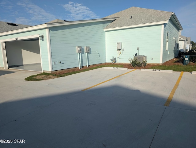 exterior space with a garage and roof with shingles