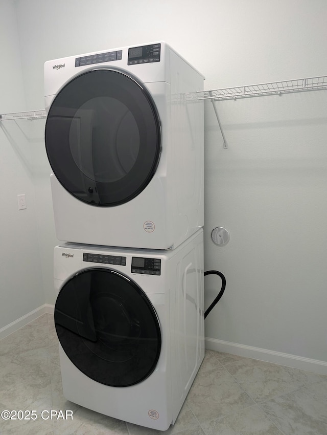 laundry room with laundry area, baseboards, and stacked washer and clothes dryer