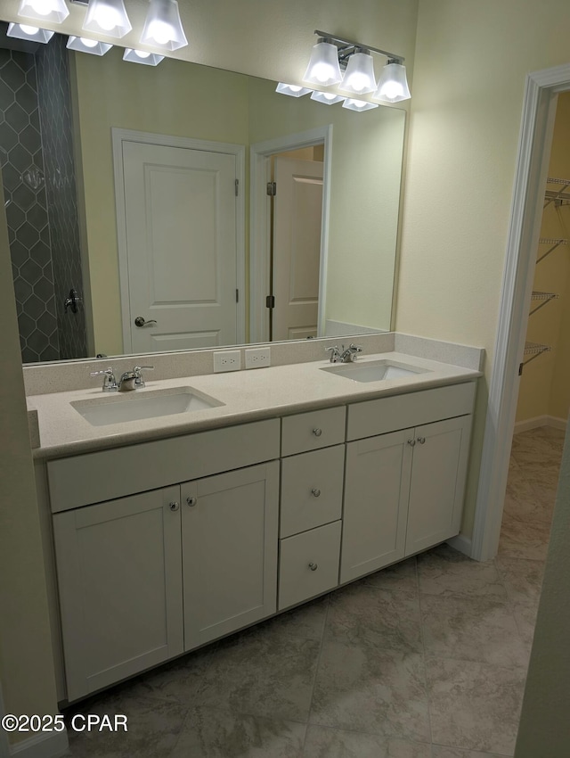 full bath featuring double vanity, a spacious closet, and a sink