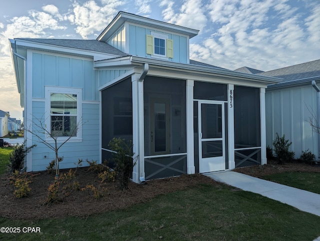 view of side of property featuring roof with shingles, board and batten siding, and a sunroom