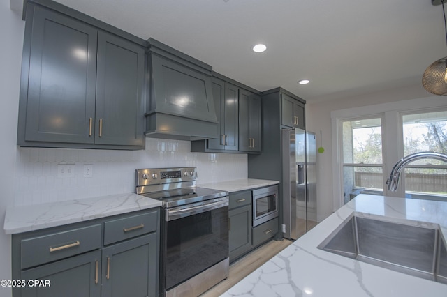 kitchen with a sink, light stone countertops, tasteful backsplash, and stainless steel appliances