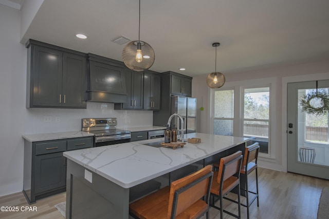 kitchen featuring a sink, stainless steel appliances, light stone counters, and premium range hood