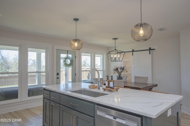 kitchen featuring gray cabinets, a sink, light wood-style floors, stainless steel dishwasher, and a barn door