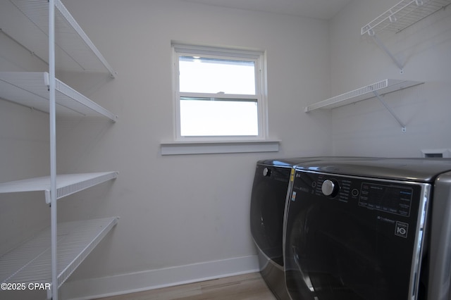 clothes washing area with laundry area, wood finished floors, baseboards, and independent washer and dryer