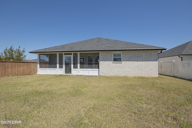 back of property with a yard, a fenced backyard, brick siding, and a sunroom