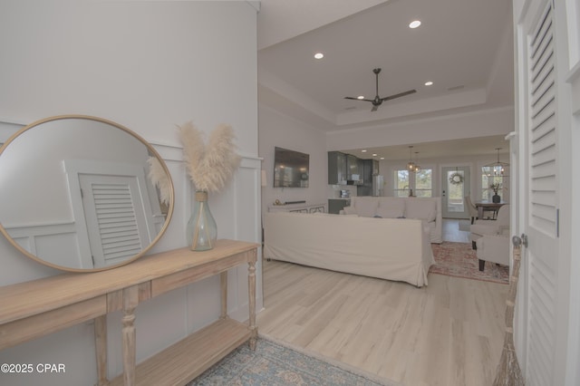 living area with recessed lighting, a raised ceiling, a ceiling fan, and wood finished floors