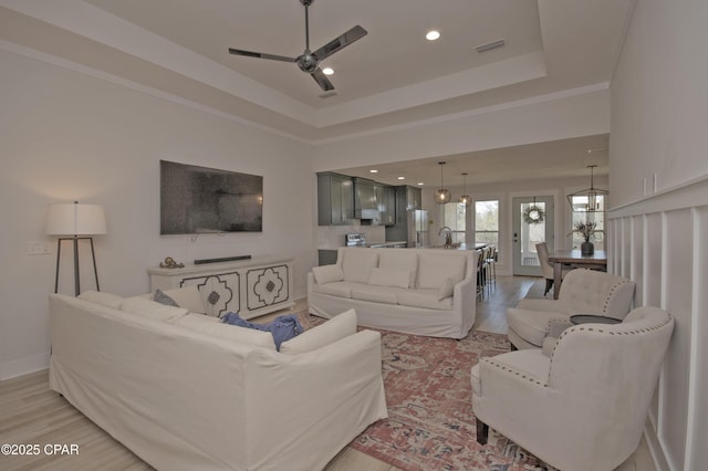 living room with visible vents, light wood-type flooring, recessed lighting, a raised ceiling, and a ceiling fan