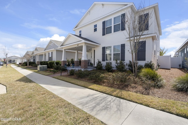 view of front of home featuring covered porch, a residential view, fence, and a front lawn