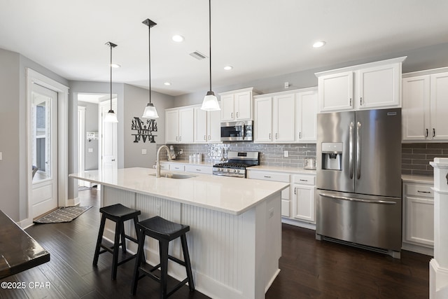 kitchen featuring white cabinets, dark wood finished floors, appliances with stainless steel finishes, light countertops, and a sink