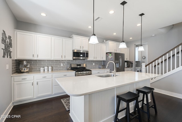 kitchen featuring visible vents, dark wood finished floors, appliances with stainless steel finishes, white cabinetry, and a sink