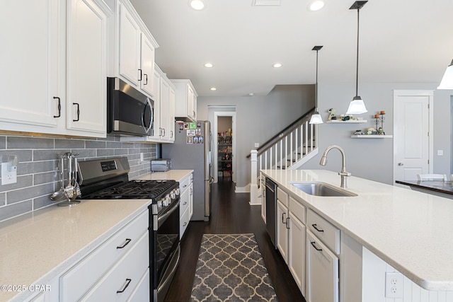 kitchen with stainless steel appliances, dark wood-style flooring, a sink, white cabinetry, and decorative backsplash