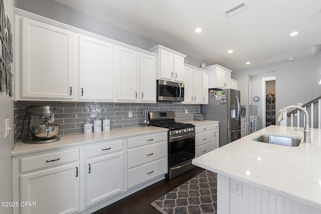 kitchen featuring stainless steel appliances, visible vents, backsplash, white cabinets, and a sink