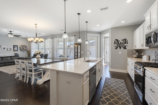 kitchen featuring visible vents, decorative backsplash, open floor plan, stainless steel appliances, and a sink