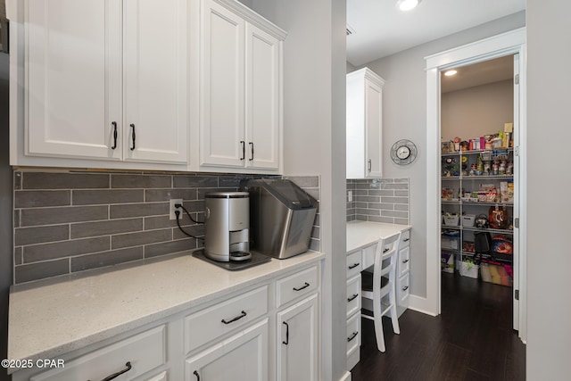 kitchen with tasteful backsplash, white cabinets, light stone counters, dark wood-style flooring, and recessed lighting