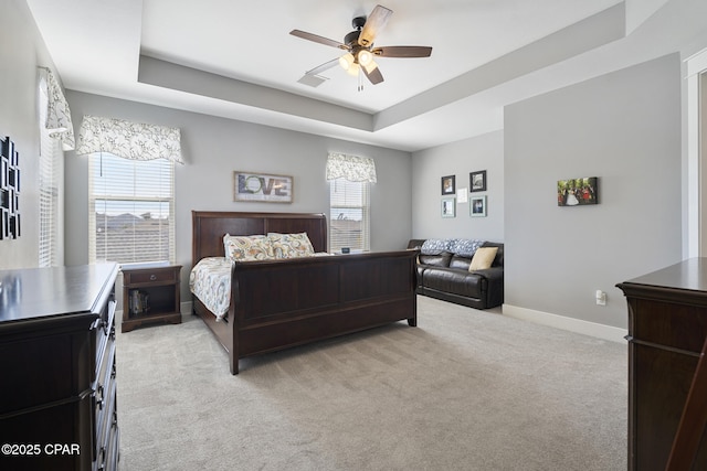 bedroom with multiple windows, a tray ceiling, and light colored carpet