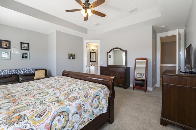 bedroom featuring light carpet, visible vents, a tray ceiling, and baseboards