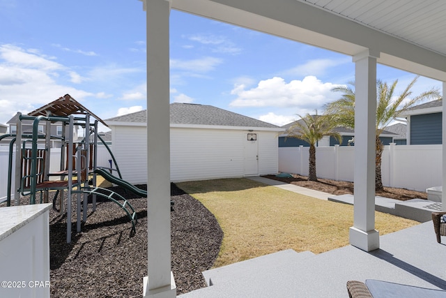 view of yard featuring fence, a playground, and an outdoor structure