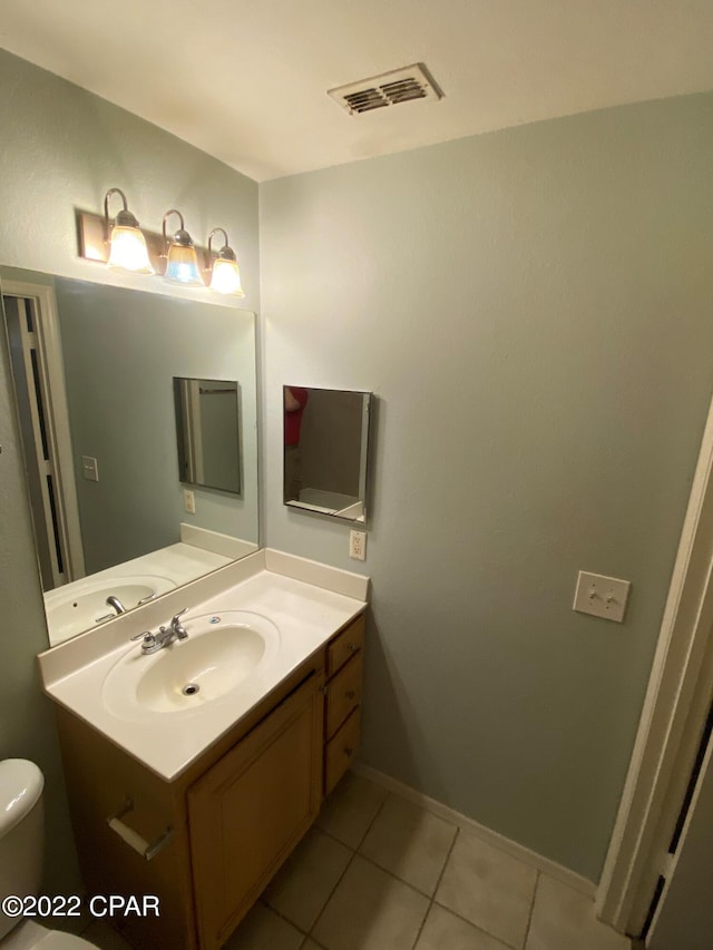 half bathroom featuring visible vents, baseboards, toilet, tile patterned floors, and vanity