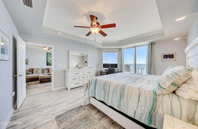 bedroom featuring visible vents, ornamental molding, baseboards, light wood finished floors, and a raised ceiling