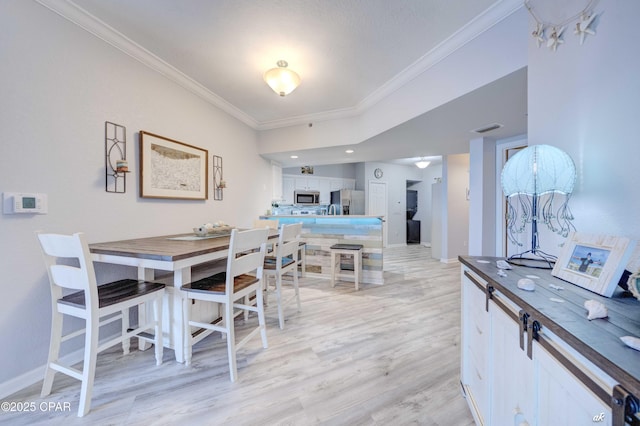 dining space with visible vents, light wood-type flooring, crown molding, and baseboards