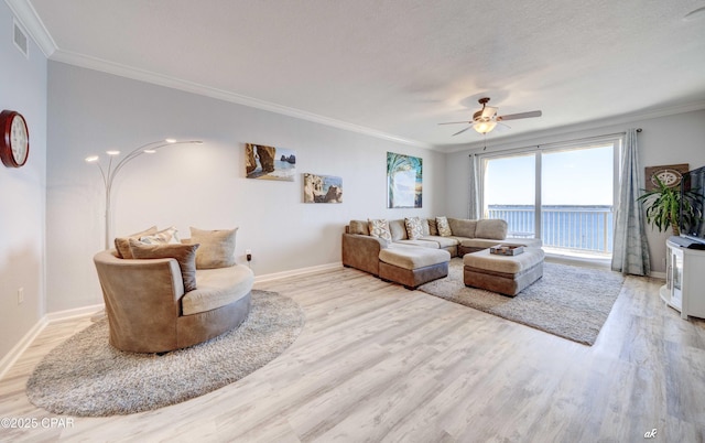 living area with ceiling fan, a textured ceiling, light wood-style flooring, baseboards, and ornamental molding