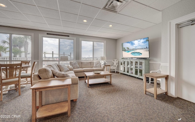 living area with visible vents, a paneled ceiling, a healthy amount of sunlight, and carpet flooring