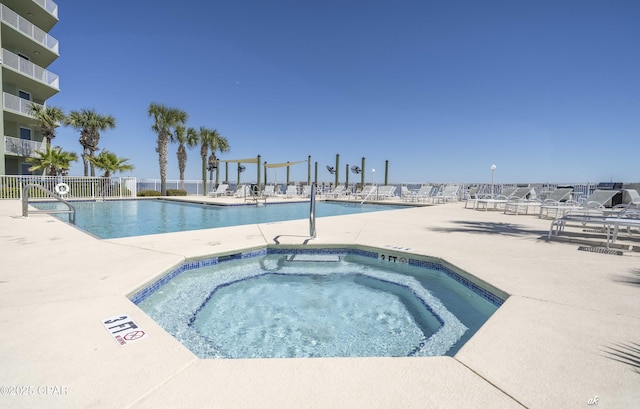 pool with a hot tub, a patio, and fence